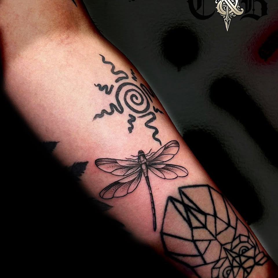 Tatuaże na ręce: ważka, spiralny symbol i geometryczne linie